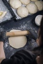 Woman in black shirt and black gloves rolling out yeast dough with a rolling pin. Process of making bakery. Adjarian Khachapuri Royalty Free Stock Photo
