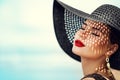 Woman in Black Summer Hat with Red Lips Make up. Fashion Luxury Model wearing Sun Hat with Shadows on Face. Women Beauty Portrait Royalty Free Stock Photo