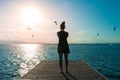 Woman in black sundress in a deck looking people doing kite surf Royalty Free Stock Photo