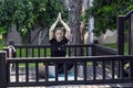 A woman in a black T -shirt does yoga on the porch of her house in the morning on a computer with a teacher remotely , around the Royalty Free Stock Photo