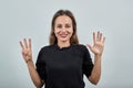 Woman in black t-shirt gray background, happy smiling girl shows eight fingers