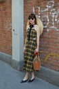 Woman with black and yellow checkered dress and wicker hat before Fendi fashion show, Milan Fashion Week street