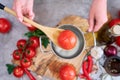 woman blanching a tomato holding over pan with hot water for further peeling