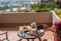 Woman blogger taking a picture on mobile phone plate with lamb potato and salad on the table outside on the balcony. Top view.