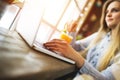 Woman blogger working at a laptop in a trendy cafe sitting at a table near the large window Royalty Free Stock Photo