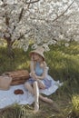 Woman with blond curly hair in luxurious dress posing in blooming spring garden Royalty Free Stock Photo