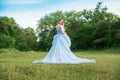 Woman with blond hair in a beautiful blue dress with a long sleeves outdoor. Romantic art photo, beautiful nature Royalty Free Stock Photo