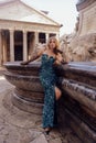 woman with blond hair in luxurious black evening dress and accessories posing near famous monument Pantheon n in Rome