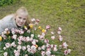 woman with blond hair near a flower bed. Portrait of a smiling girl Royalty Free Stock Photo