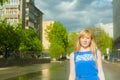 Woman blonde in blue dress walking along a city street against a background of urban architecture and summer Siberian beauties Royalty Free Stock Photo