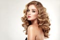 Woman blonde with voluminous, shiny,curly and loose hairstyle.