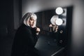 Woman in blonde wig and black coat in dressing room Royalty Free Stock Photo