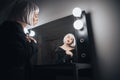 Woman in blonde wig sitting near mirror in dressing room Royalty Free Stock Photo