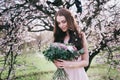 Woman in blooming trees. Woman with wedding bouquet in hands.