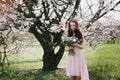 Woman in blooming trees. Woman with wedding bouquet in hands.