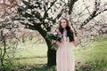 Woman in blooming trees. Woman with wedding bouquet in hands.