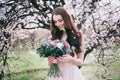 Woman in blooming trees. Woman with wedding bouquet in hands.