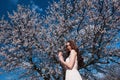 Woman in blooming trees. Woman with wedding bouquet in hands.