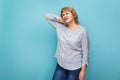 A woman in a blouse and jeans stands on a blue green background Royalty Free Stock Photo