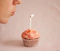 Woman blowing a candle on a pink cupcake Royalty Free Stock Photo