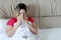 Woman blowing her nose in a handkerchief sitting in a bed Royalty Free Stock Photo