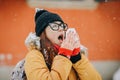 Woman blowing her nose with a tissue outdoor in winter. Young woman getting sick with flu in a winter day Royalty Free Stock Photo