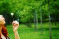 Woman blows away a dandelion among the trees