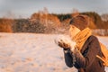 A woman blows a handful of snow from her hands at sunset in the evening Royalty Free Stock Photo
