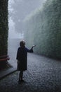 Woman in a blu coat, in an ancient public garden in a thick fog.