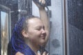 Woman with blue afro hairstyle in the shower is washed with water