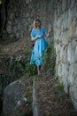 A woman in a blue airy dress in medieval ruins.
