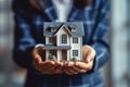 woman in blue business suit holds model of an apartment building in her palms,hands in close-up,concept of mortgage lending,real