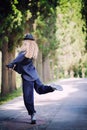 Woman in blue clothes and a hat in a dancing pose on an alley in the park. Street dancer Royalty Free Stock Photo