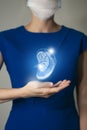 Woman in blue clothes holding virtual volumetric drawing of spleen in hand.