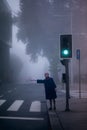 A woman in a blue coat votes in the street in a thick fog.