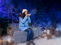 Woman in blue down jacket blows snowflakes while sitting on a sw Royalty Free Stock Photo