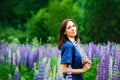 A woman in a blue dress on a purple field of lupins. Meadow with purple flowers in summer. A girl with long hair holds a bouquet Royalty Free Stock Photo