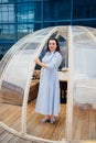 woman in a blue dress stands in a cafe in the shape of a igloo on roof.