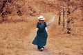 A woman in a blue dress walks along a path in an autumn park, back view Royalty Free Stock Photo