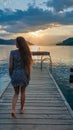 A woman in a blue dress walks along a wooden pier of Millstaettersee lake and enjoys the sunset. The sun is setting Royalty Free Stock Photo