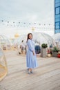 woman in a blue dress walks in a cafe in the shape of a igloo on roof.