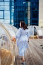 woman in a blue dress walks in a cafe in the shape of a igloo on roof.