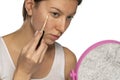 Woman with blue eyes applying concealer under her eyes