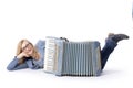 Woman in blue with glasses lies behind accordeon and smiles