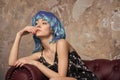 Sensual woman with blue hair wig. Woman with stylish hair relax on sofa. Beauty girl with glamour look and makeup