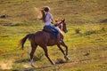 Woman in blue jeans riding a horse