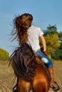 Woman in blue jeans riding a horse