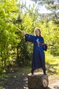 A woman in a blue kimono poses with a sword in the forest standing on a stump Royalty Free Stock Photo
