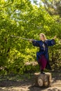 A woman in a blue kimono poses with a sword in the forest standing on a stump Royalty Free Stock Photo