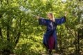 A woman in a blue kimono poses with a sword in the forest standing on a stump Royalty Free Stock Photo